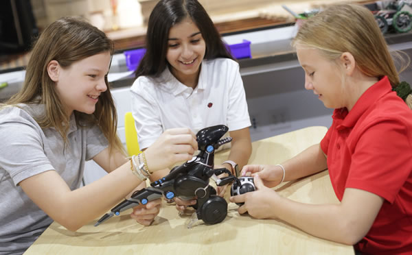 Girls testing out a robotic dinosaur in the classroom